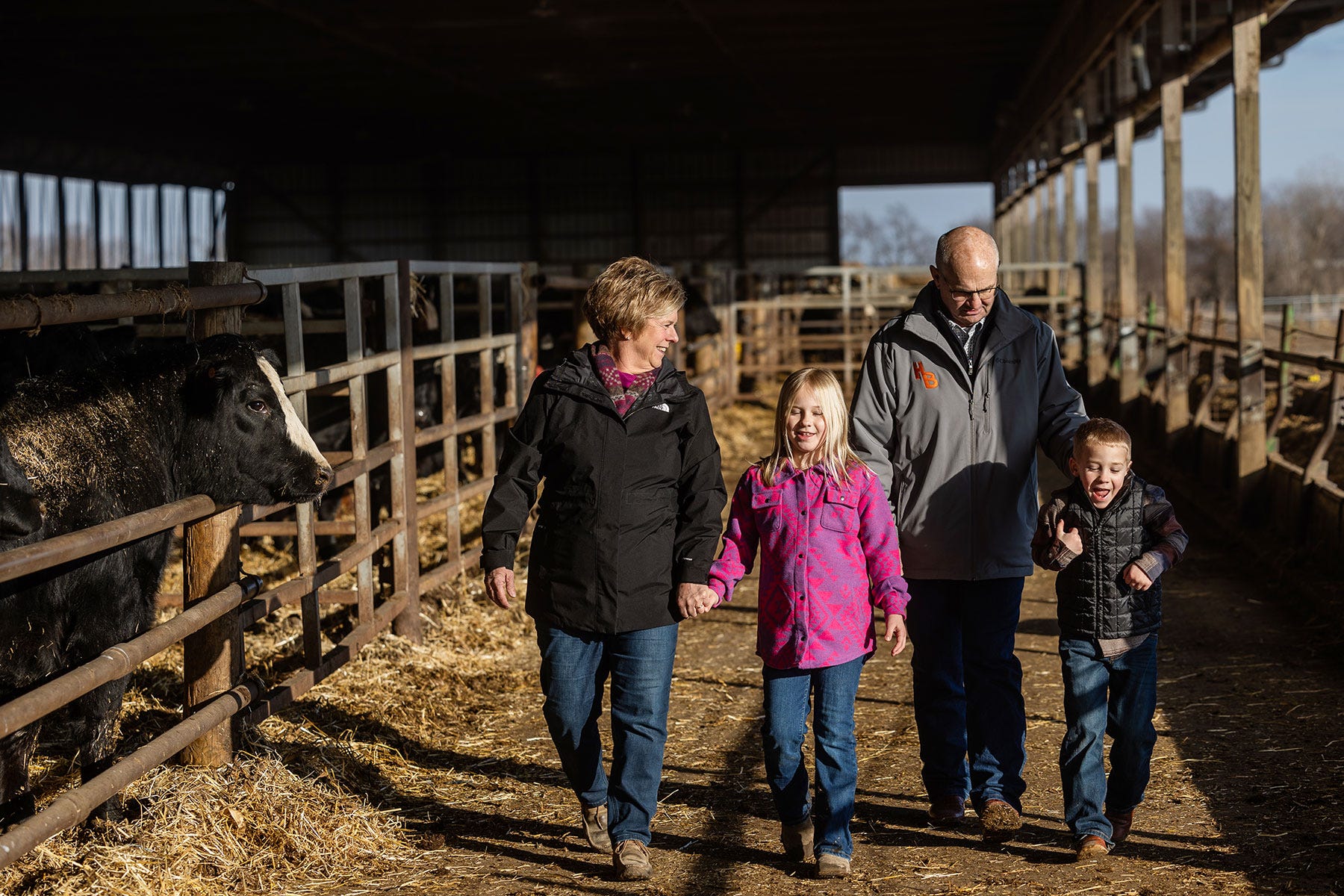Malcolm and Susan Head and two grandkids walk through a cattle barn