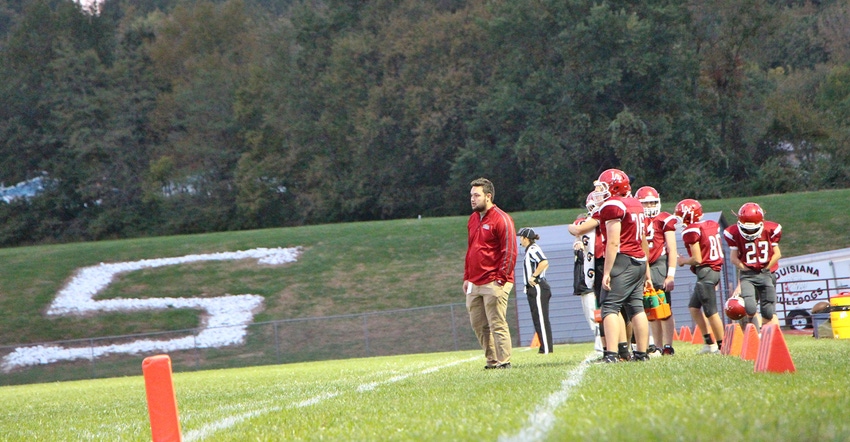 coach and players on sidelines of a middle school football game