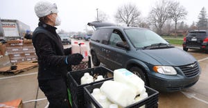 Woman handing out milk to cars as they drive through at a food bank