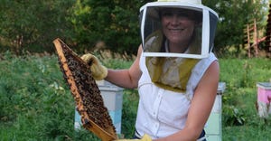 Megan Vetter, president of Nebraska Beekeepers Association holding a honey bee frame from a honey bee box