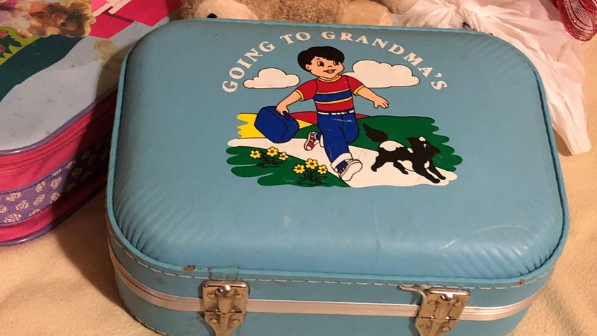 small, blue child's suitcase that says "Going to Grandma's"