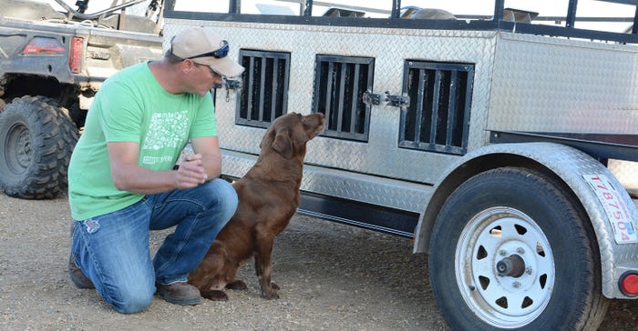 Travis Strasser and his dog, Moxie next to trailer