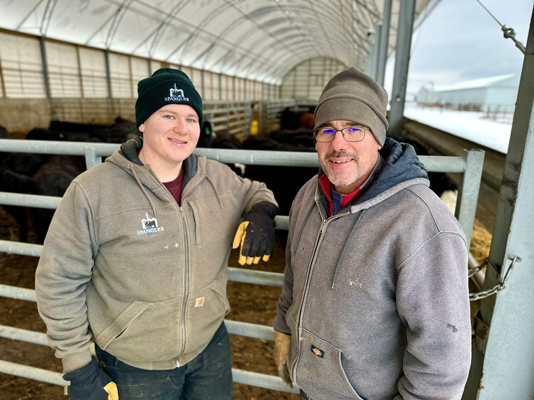 A father and son pose in a cattle building