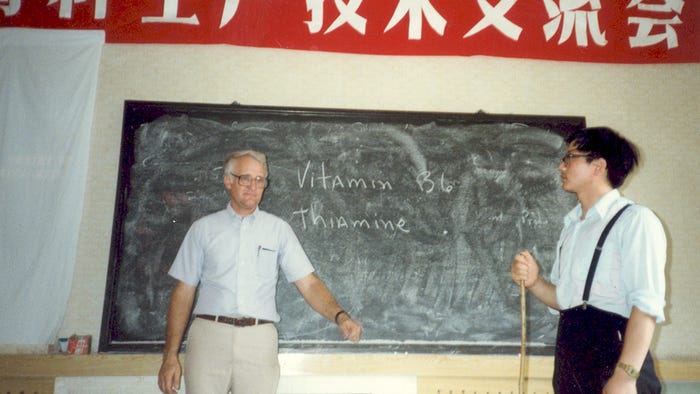Bob Easter and a Chinese man stand in front of a chalkboard