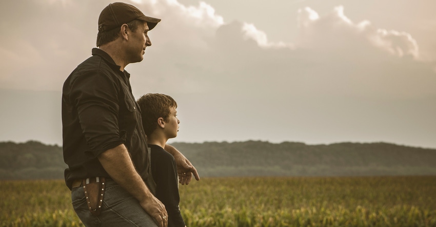 father and young son overlook cropfields