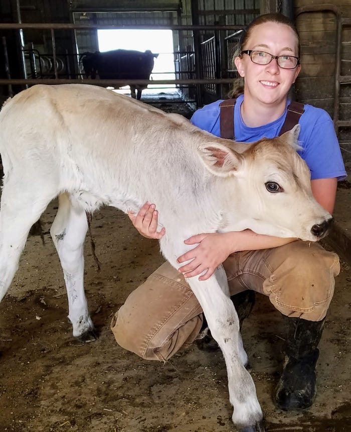 Sarah Morrison, research scientist at Miner Institute, kneels beside a calf