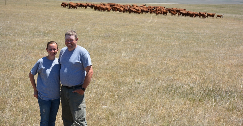 Crystal and Levi Neuharth winners of South Dakota Leopold Conversation Award standing in field with cattle behind them