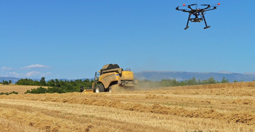 UAV filming a combine harvester in wheat field