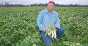Mike Andrew kneeling in field of cover crops