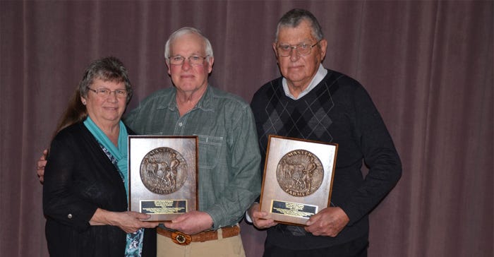 A woman and two men stand to pose while holding Master Farmer plaque awards