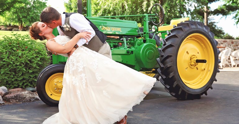 Jake and Ashley Standal kiss in front of John Deere tractor on wedding day
