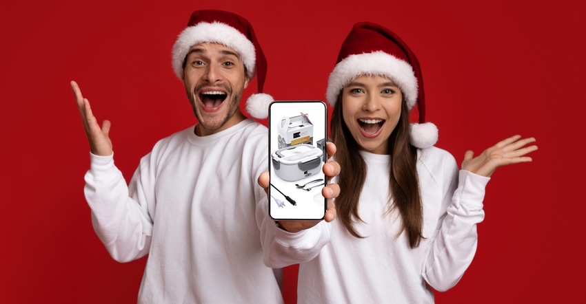 Excited man and woman in Santa hats holding cell phone