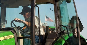 closeup on John Deere tractor cab with man in cab