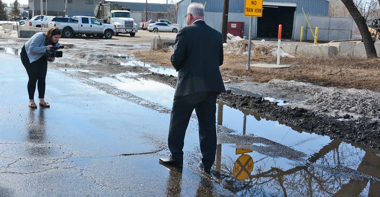 Gov. Tim Walz posed by  pothole for media