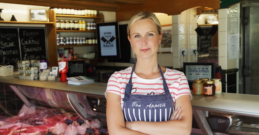 Female butcher in shop in front of meat case