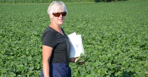 Betsy Bower standing in soybean field with clipboard
