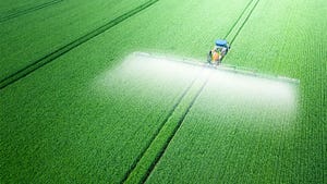 An aerial of a tractor spraying a field with fertilizer