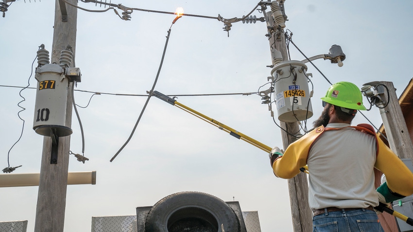 person holding Hot dog on pole touching power lines