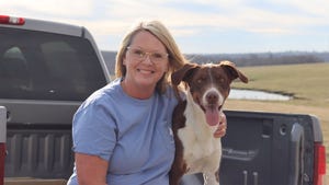 Renee Fordyce sits on a bed of a pickup truck with a dog