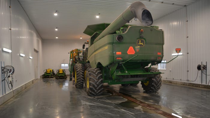 John Deere combine parked in farm shop wash bay John Deere combine parked in farm shop wash bay