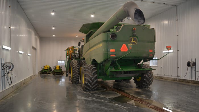 John Deere combine parked in farm shop wash bay