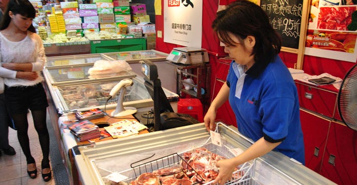 Woman arranges cuts of pork in wet market in Guangzhou, China.
