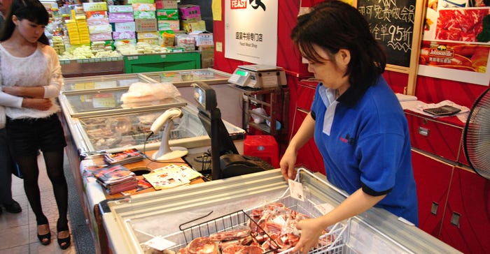 Woman arranges cuts of pork in wet market in Guangzhou, China. Woman arranges cuts of pork in wet market in Guangzhou, China.