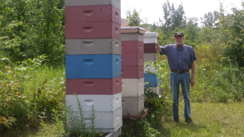 A beekeeper standing next to stacked beehives