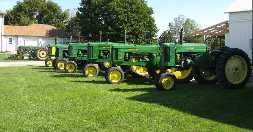 A row of yellow and green John Deere tractors lined up