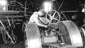  An old black and white photograph of a young man working on a tractor