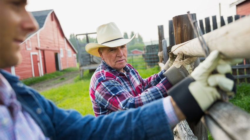 Older farmer, young farmer fix fence together