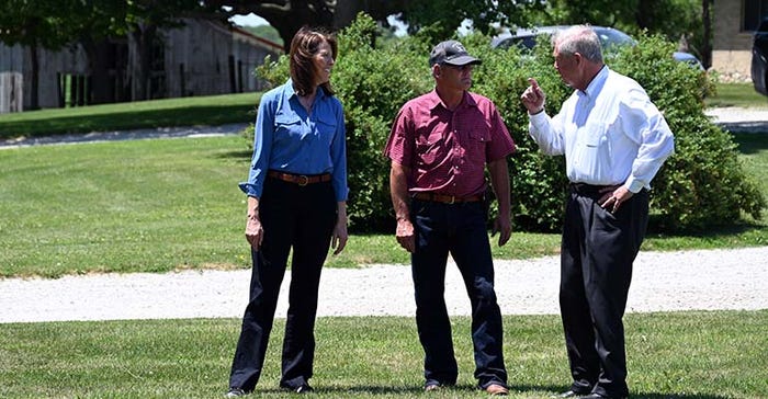 Cindy Axne and Iowa farmer Chris Nelson listen to U.S. Secretary of Agriculture Tom Vilsack
