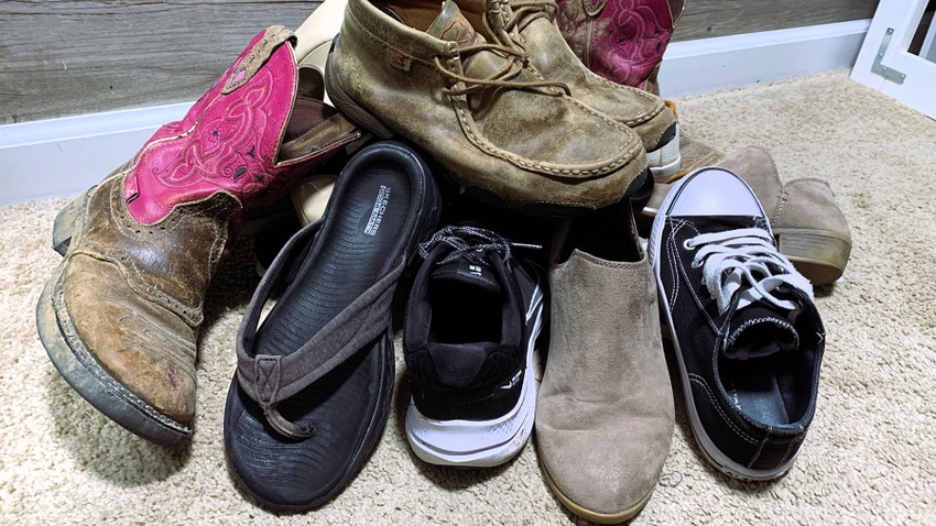 Various styles of shoes in a pile on the floor