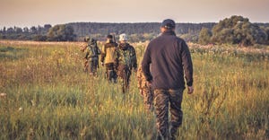 hunters walking through field single file