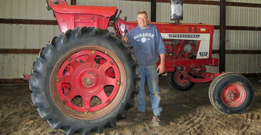 Steve Schluter standing next to a 1976 International 666 Farmall tractor