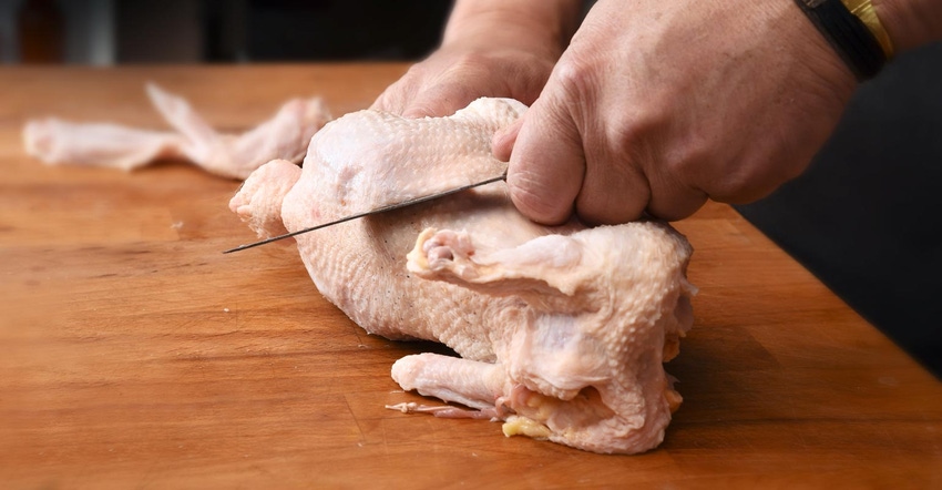 Male hands preparing a raw chicken on a wooden tabletop