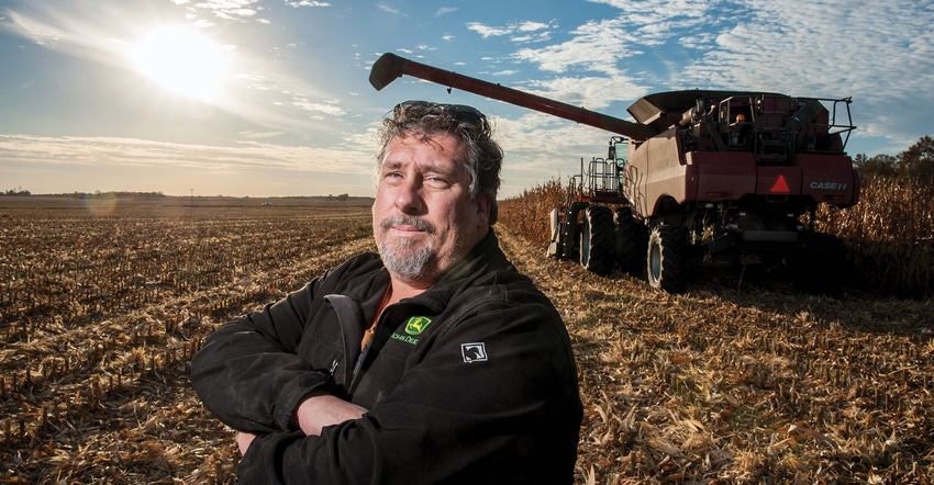 Farmer posed in front of combine in corn field