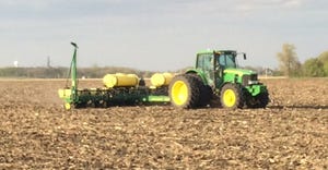 A farmer plants corn with a John Deere tractor