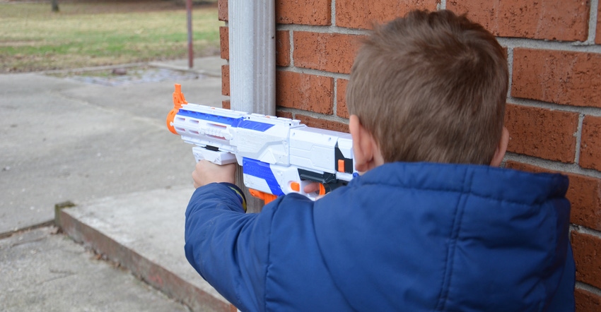 10-year-old boy taking aim with Nerf gun