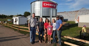 Mark Kja, Laurie Kjar,  Beth Frerichs, Pam and Tyler Nelson with their daughter standing in front of a mini grain bin Chief d