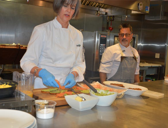 Chef Janet Bourbon, left, creates a salmon, avocado and scrambled egg on toast appetizer as Chef Steven Junta looks on