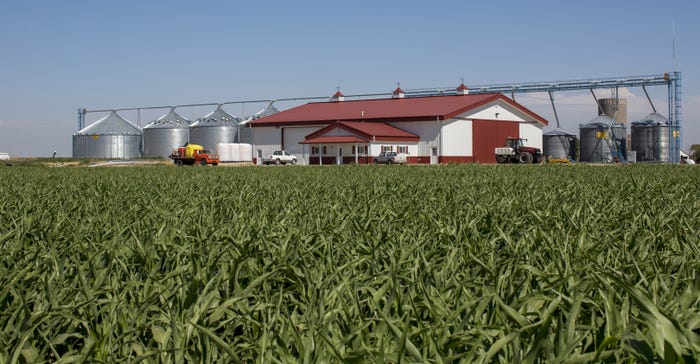 cornfield in front of Morton Buildings farm shop with grain center behind it