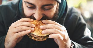 man wearing hat biting into burger
