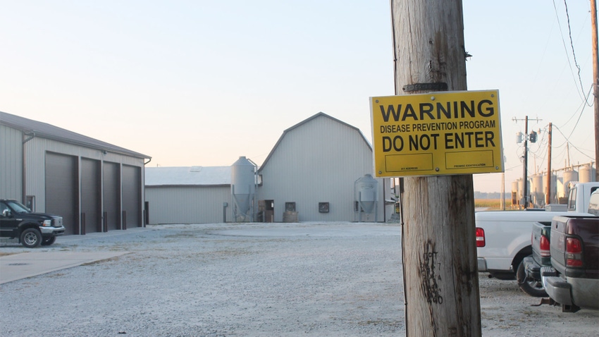 A yellow "warning, do not enter" sign near a farm facility