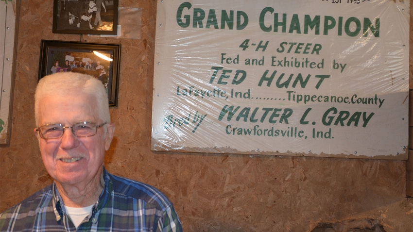 Ted Hunt smiles while standing next to a 4-H grand champion sign