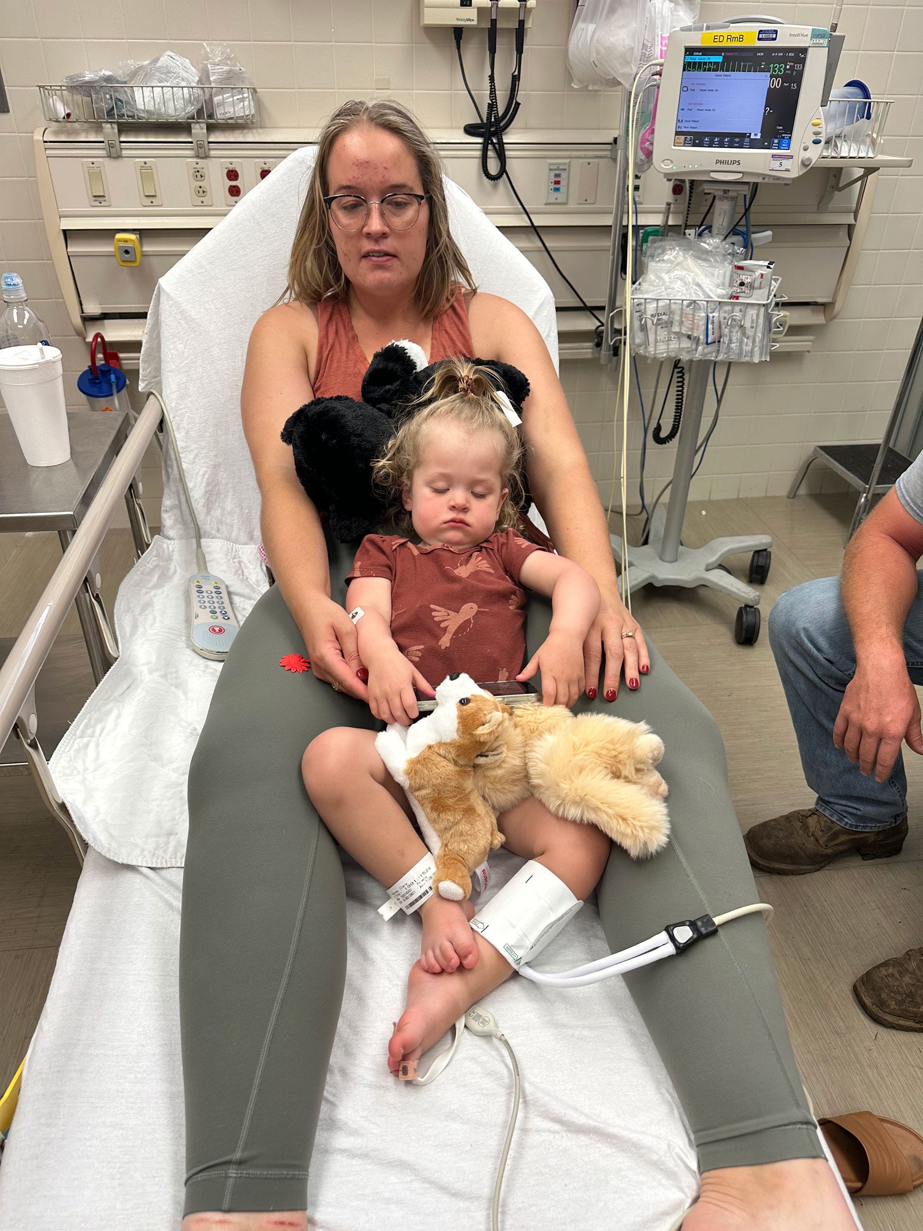 a mom and her toddler daughter lie in a hospital bed together