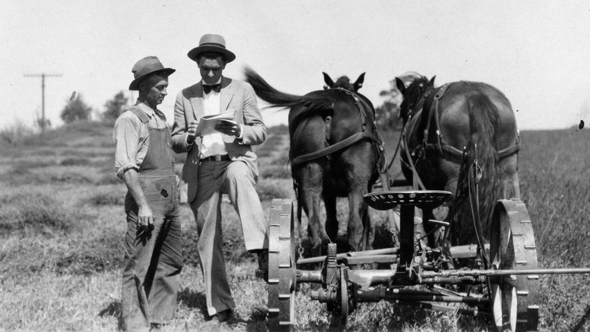 black-and-white image of farmer and Extension agent standing next to horses pulling a farm implement