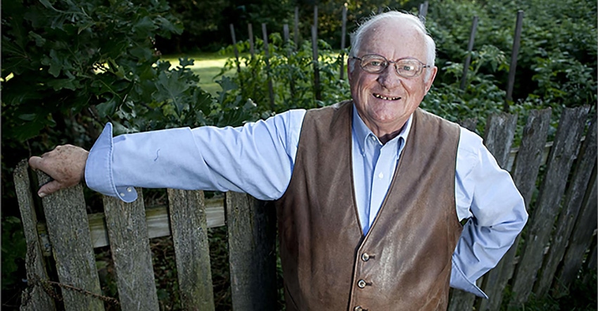 Jerry Apps leaning on a wooden fence in his garden