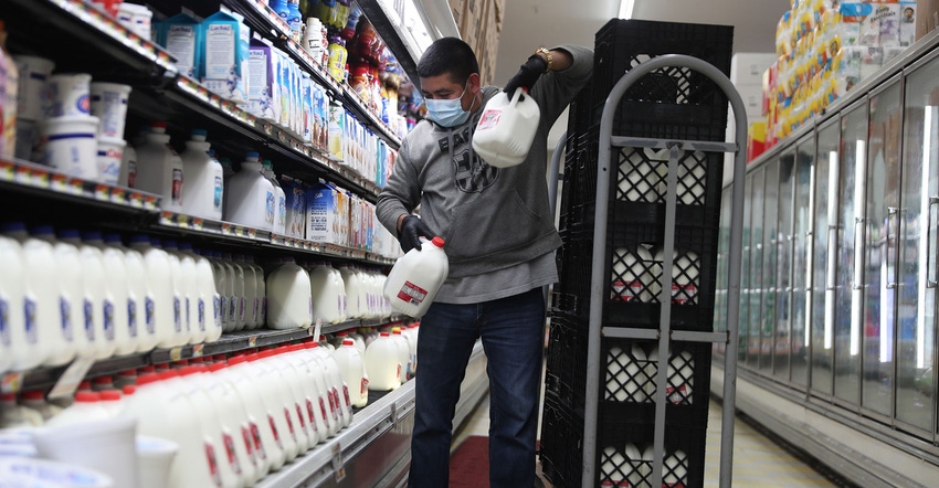 A worker restocks milk shelves at a grocery store