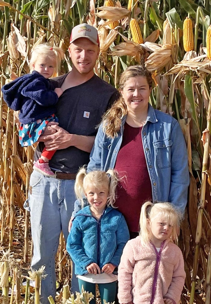  Nicholas Jerabek holds his daughter, Caraline, and poses in the yield contest field last fall with his family —including his wife, Tess, and their other daughters Avery and Josie